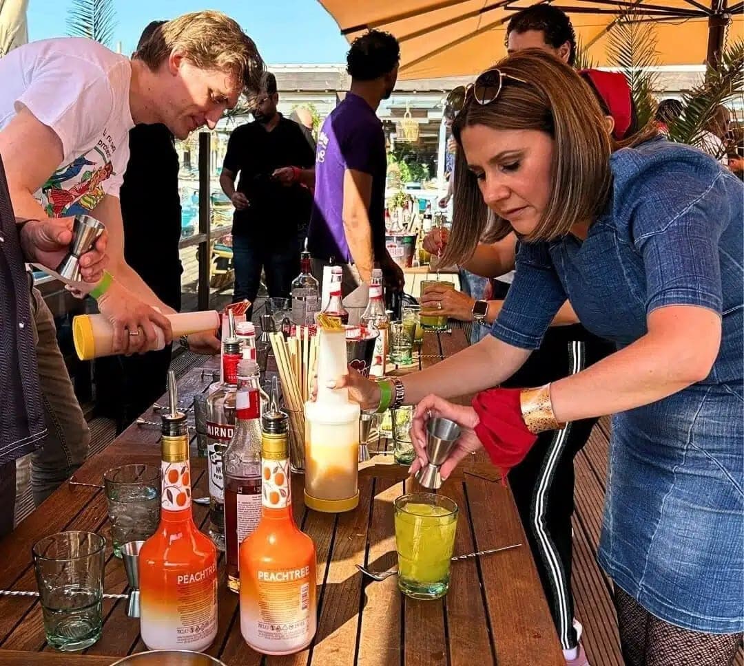 Deelnemers meten en mixen cocktails aan een bartafel tijdens de workshop