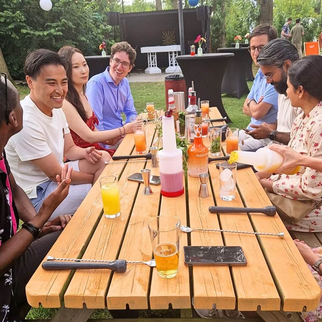 Team zit samen aan de bartafel tijdens een cocktailworkshop als bedrijfsuitje